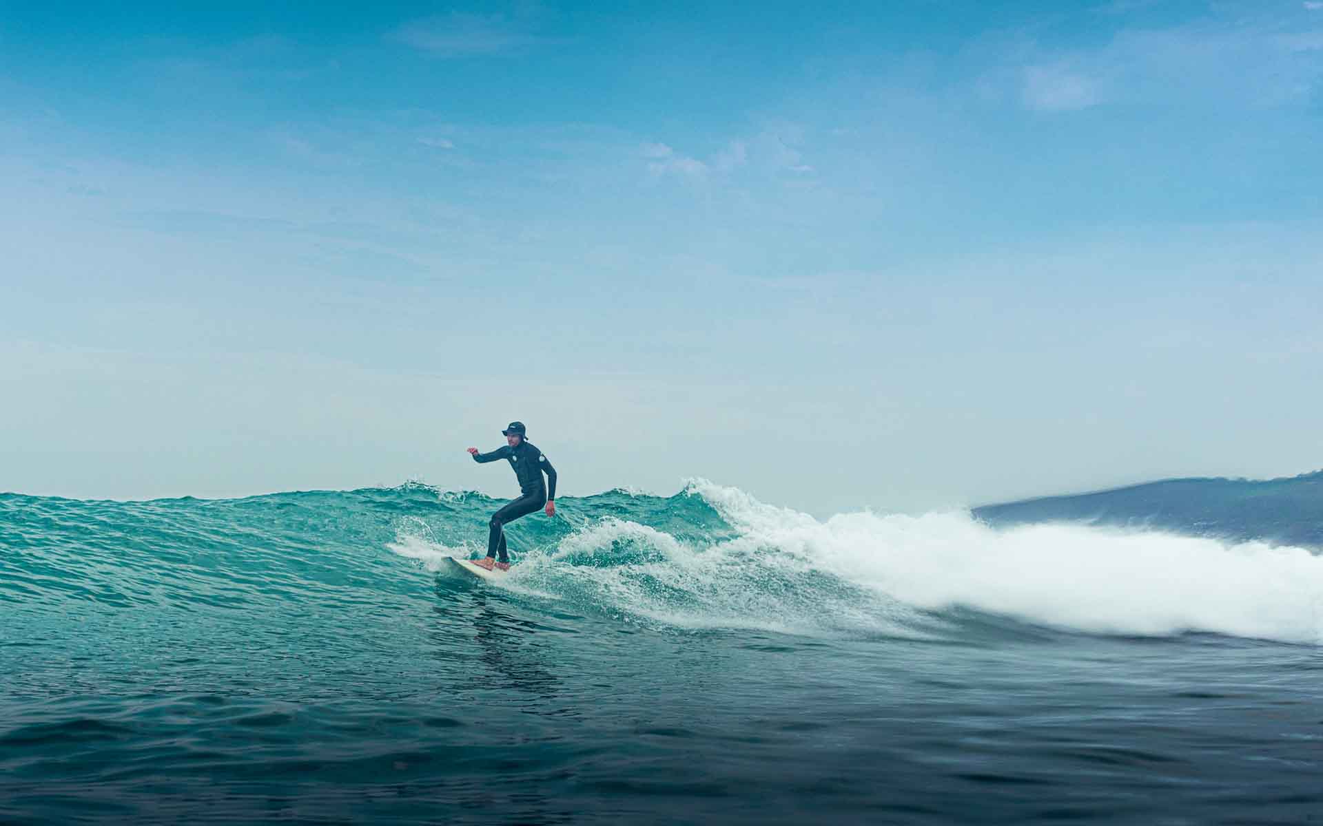 student on wave with hat